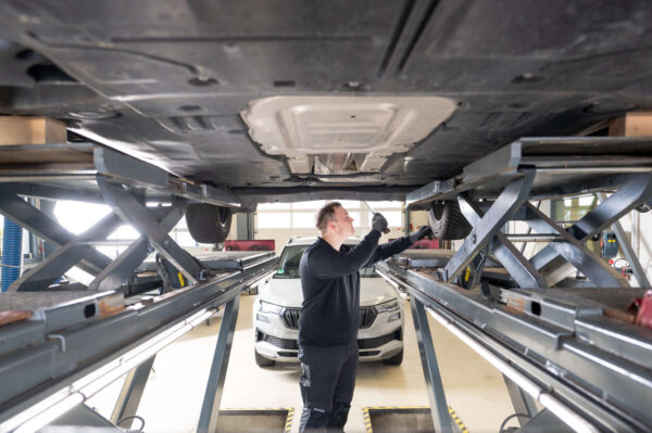 Prüfer steht unter dem Auto und führt eine HU durch